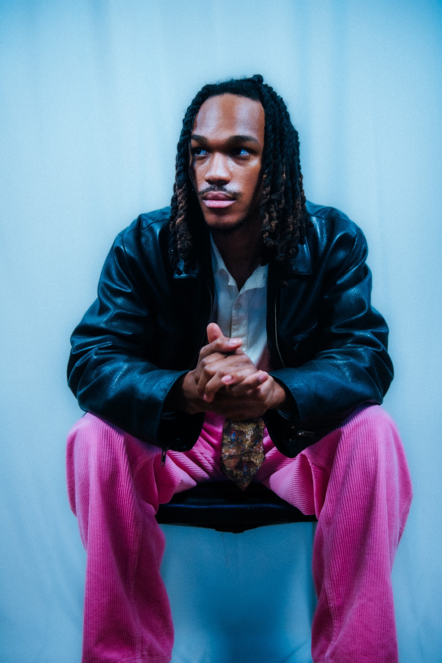 Kamari seated and leaning forward in a fashion portrait