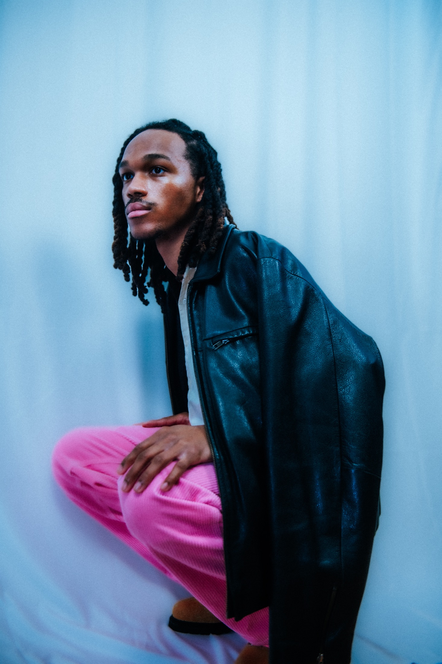 Kamari posing in a black jacket and pink pants