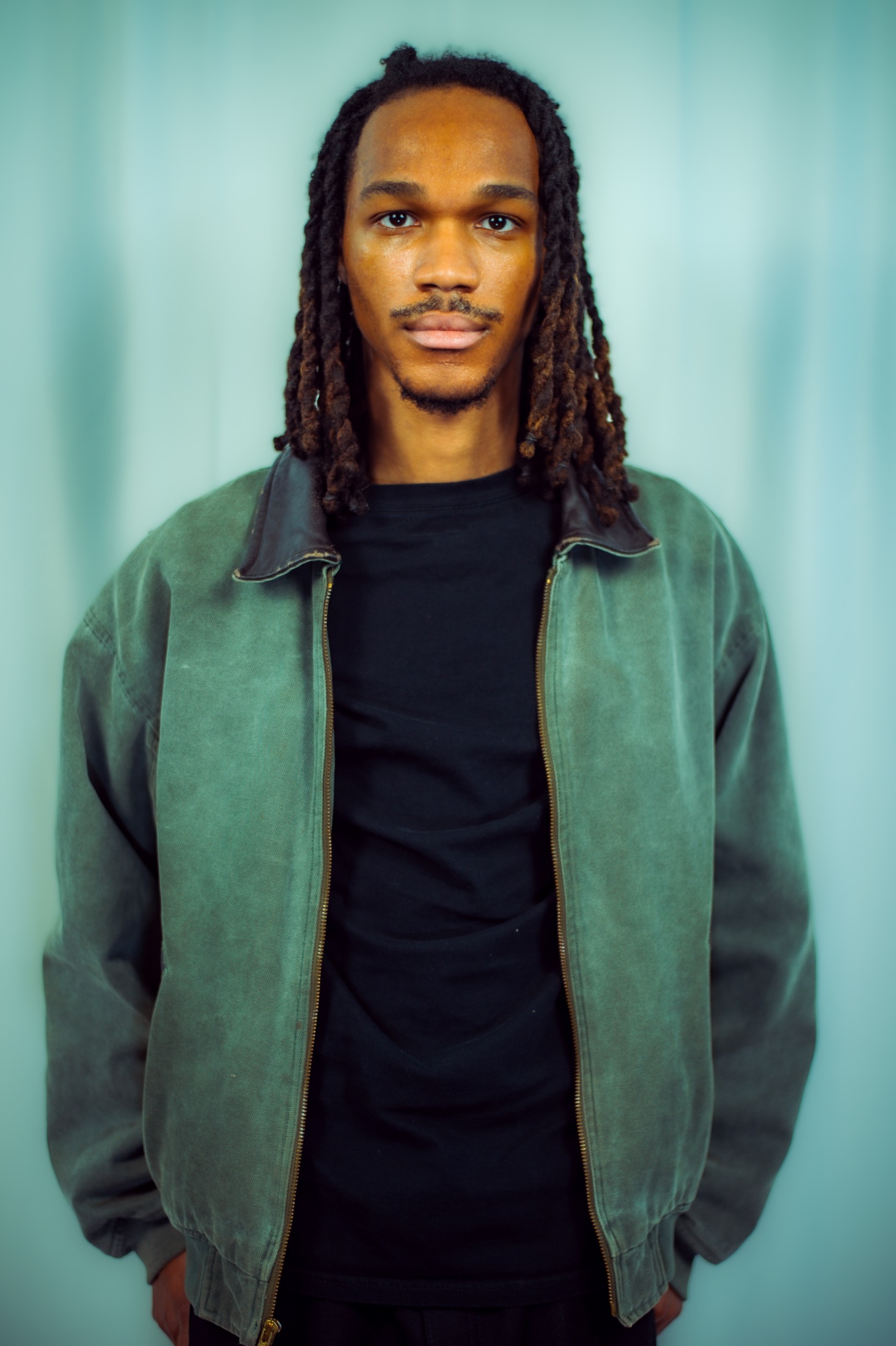 Kamari wearing a green jacket against a blue backdrop
